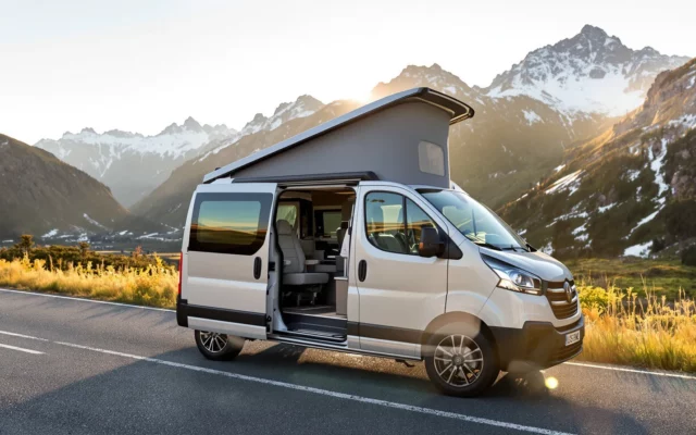 Van aménagé garé sur une route de montagne au coucher du soleil