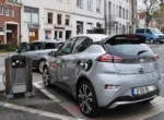 Voiture électrique compacte branchée sur une borne de recharge en ville
